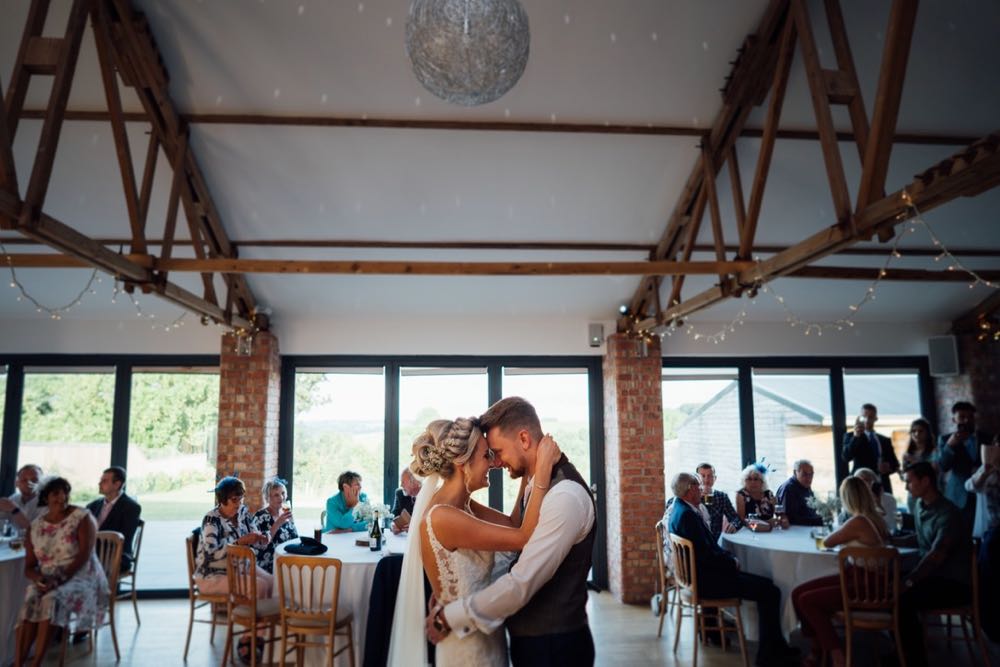 A picture taken in the Red Brick Barn. The shot is of the first dance. The couple are shown with the large window s in the background.