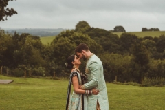 Couple in Indian wedding dress in front of the view in front of the Red Brick Barn