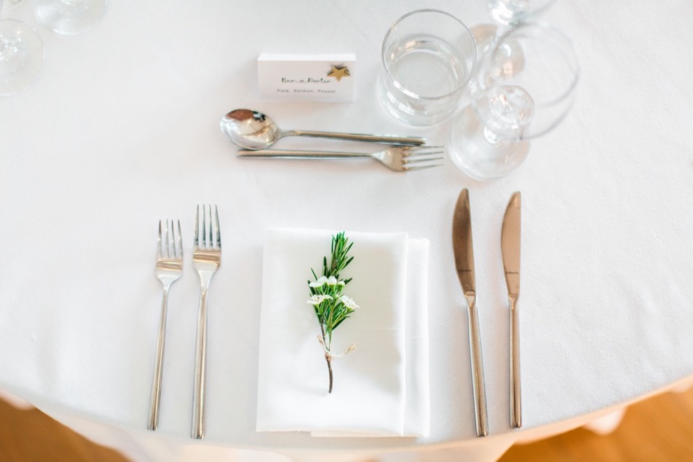 Table set up with round tables, white linen and greenery for a place setting