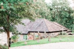 This is an image of cottage number 2. This detached cottage that sleeps 4 people. It is made of local cob that is gray and brown in colour. it has a grey slate roof. The cottage is surrounded by greenery.