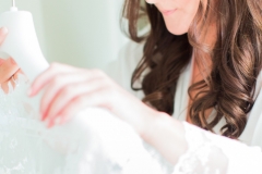 A close up shot of the bride holding her veil while getting ready. She has long dark hair that she wears loose.