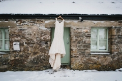 A white wedding dress hanging up outside above the front door of cottage number one. There is snowdon the ground