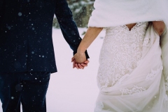 A close up of the couple holding hands outside in the snow
