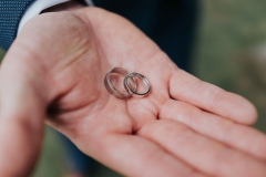 A close up of a man\'s hand holding a 2 wedding rings