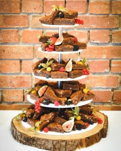 Five Tiers of Chocolate Brownies on a cakestand decorated with fruit on a log cake stand